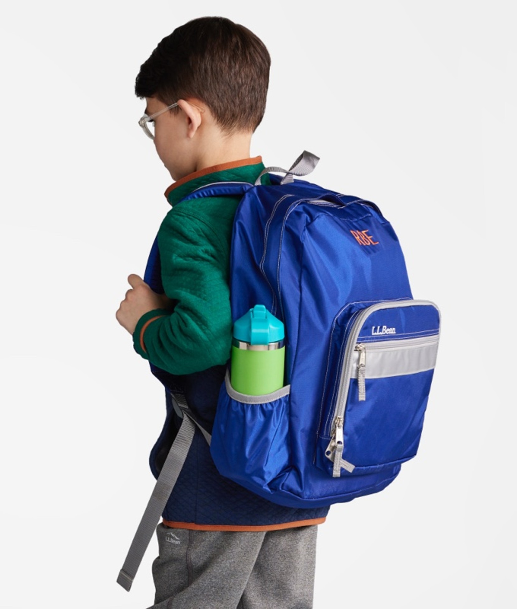 A young boy wearing a school backpack turned away from the camera so the backpack is shown at 3/4 view.