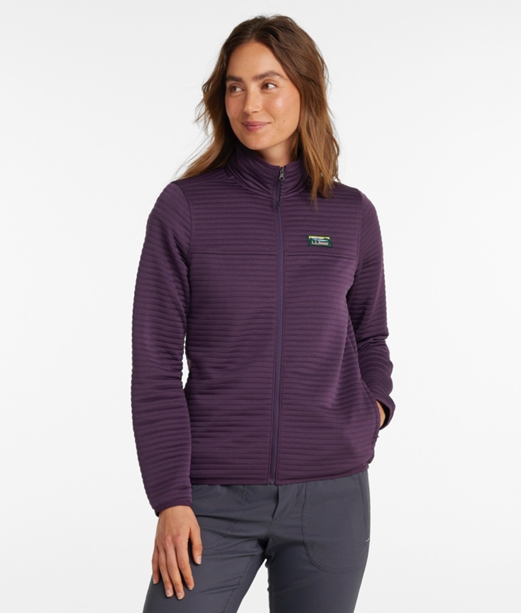 A thigh-up shot of a woman wearing a zip-front lightweight jacket and pants.