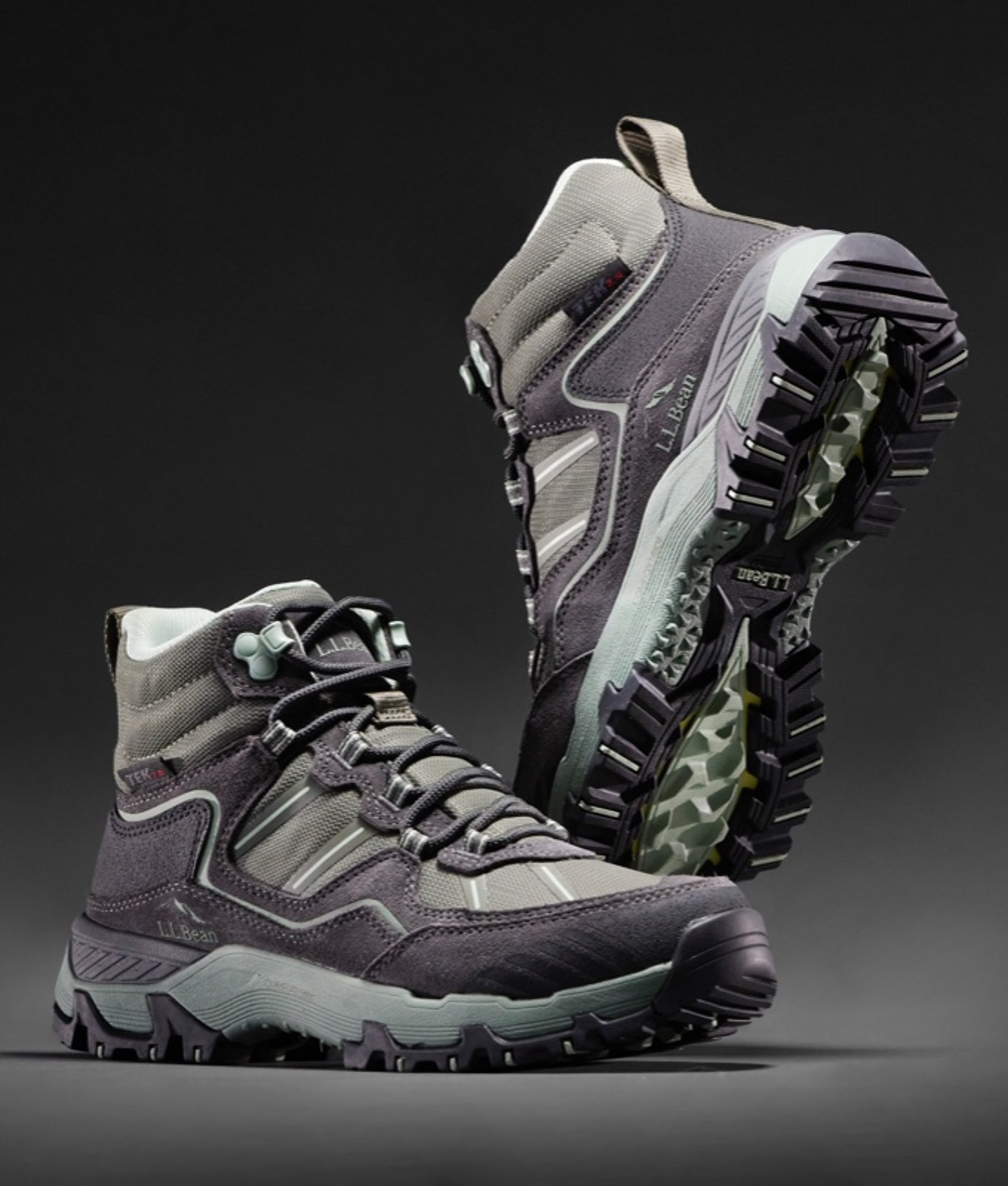 A pair of women's hiking boots, one 3/4 view and the other 3/4 view on its toe showing the tread.