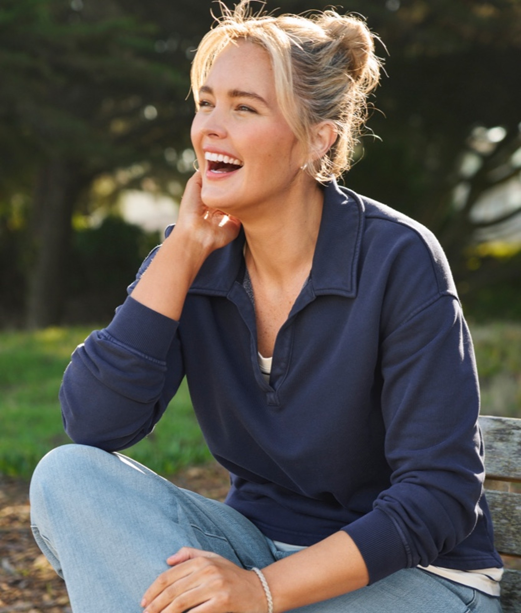 Laughing woman sitting outside on a wooden bench.