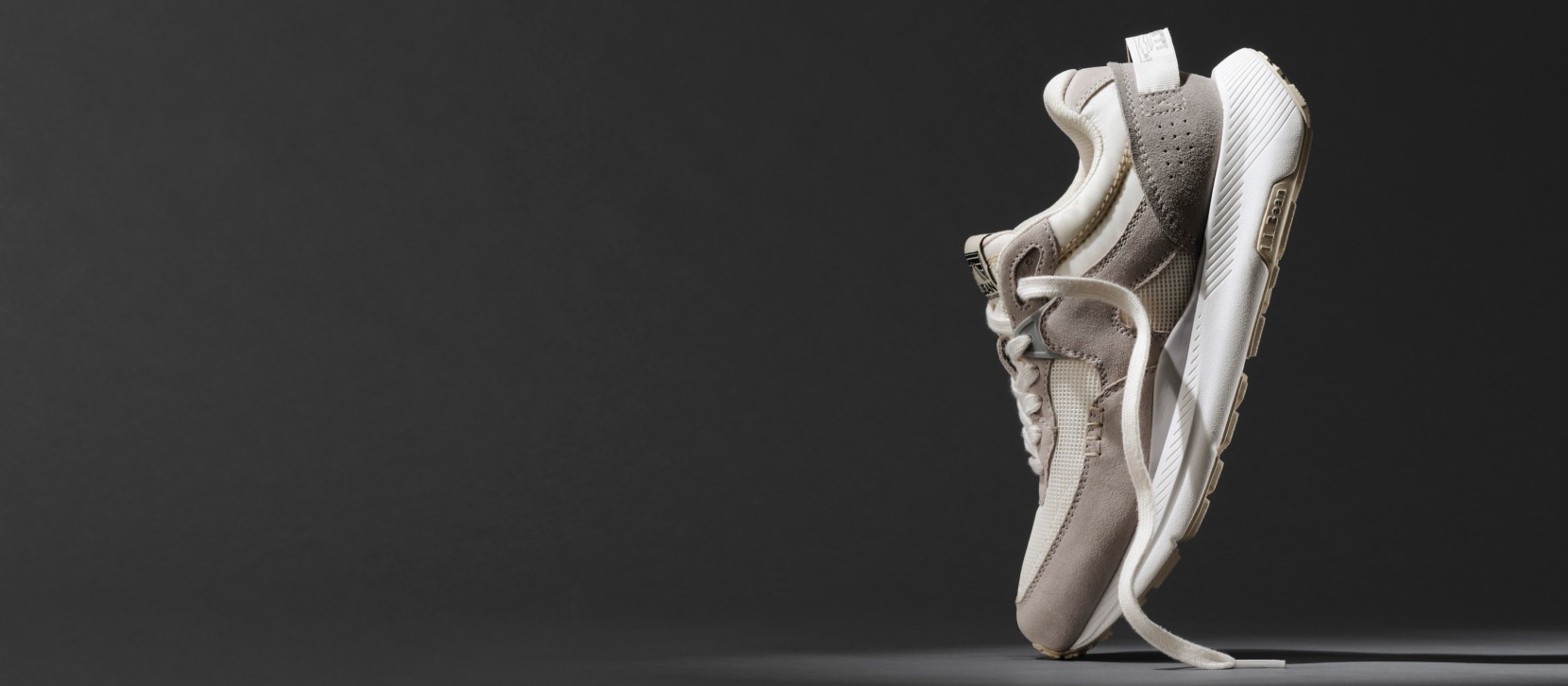 A Mountain Classic sneaker perched on its toe with a dark background.