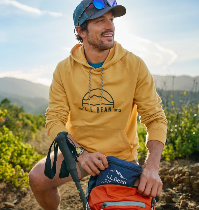 Man opening his backpack, mountains in the background.
