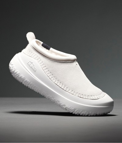 White slip-on slippers with textured sole and heel loop, shown against a gray background.