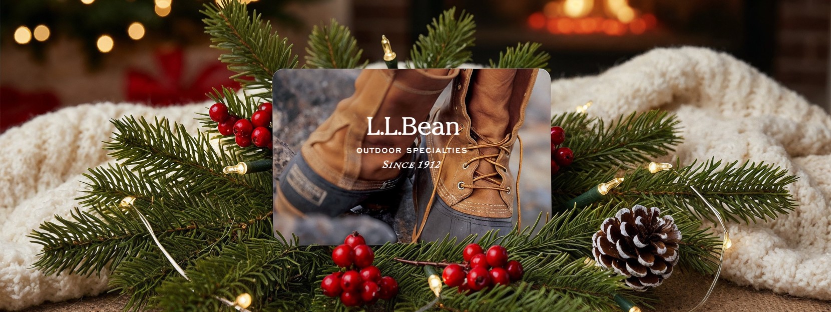 L L Bean gift card displayed on pine branches with red berries, pinecone, and holiday lights.