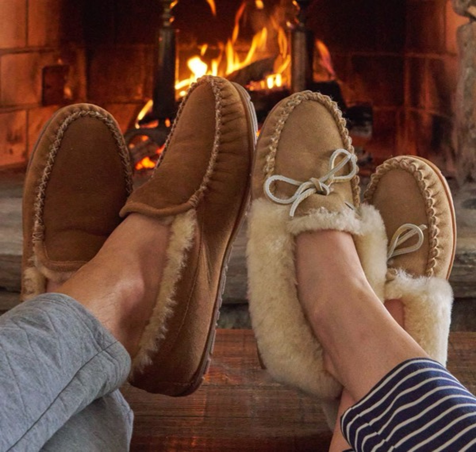 Couple sitting in front of a fire with Wicked Good Slippers