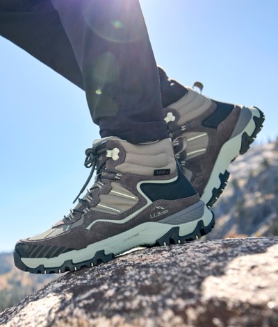 L. L.Bean hiking boots on rocky terrain with rugged soles, set against a scenic mountain backdrop.