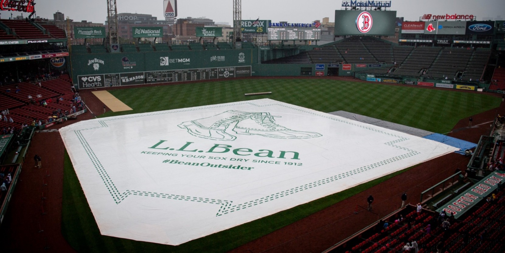 Fenway Park field covered by L L Bean tarp with slogan "Keeping Your Sox Dry Since 1912" and hashtag BeanOutsider.