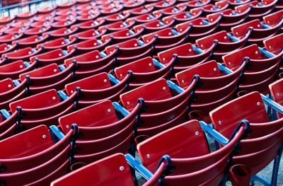 Rows of empty red stadium seats with blue armrests, arranged in a repeating pattern. 