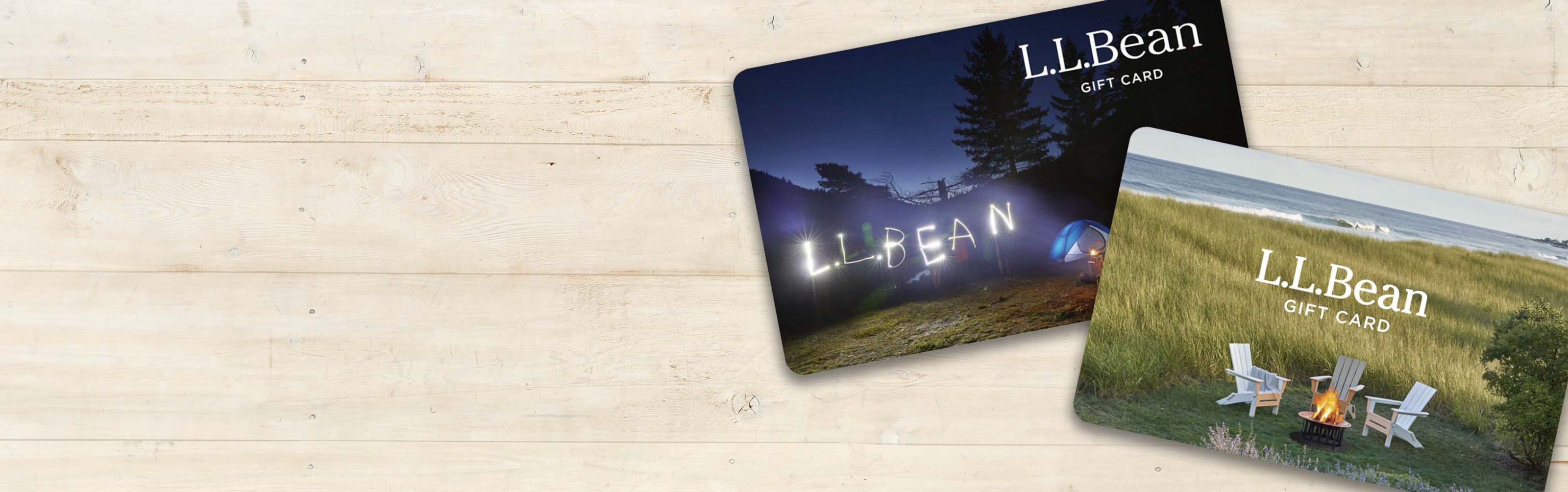 2 L L Bean gift cards on a light wood background.