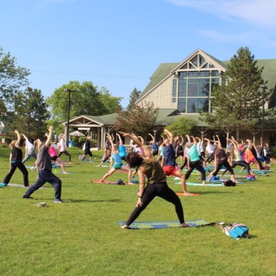 A group of people enjoying a yoga class outside the L. L. Bean store on the green grass on a sunny day.