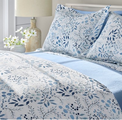 A bed with blue and white floral bed sheets.