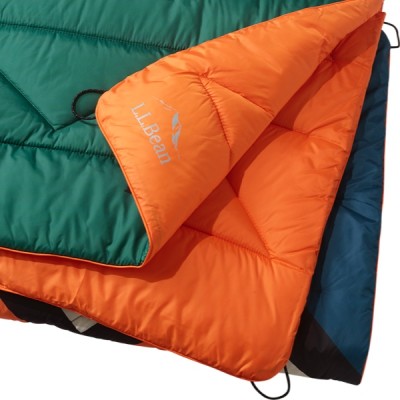A quilted, reversible camping blanket with one side green and the other orange.