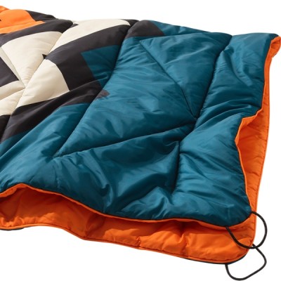 A blanket with a geometric pattern, featuring blue, orange, black, and white sections.