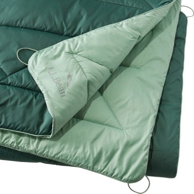 A quilted, reversible camping blanket with one side green and the other mint green.