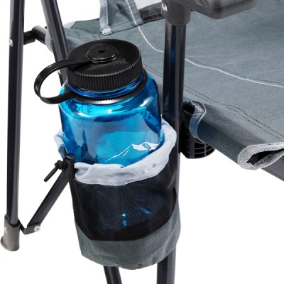 A blue water bottle is placed in a holder attached to the leg of a green folding chair. 