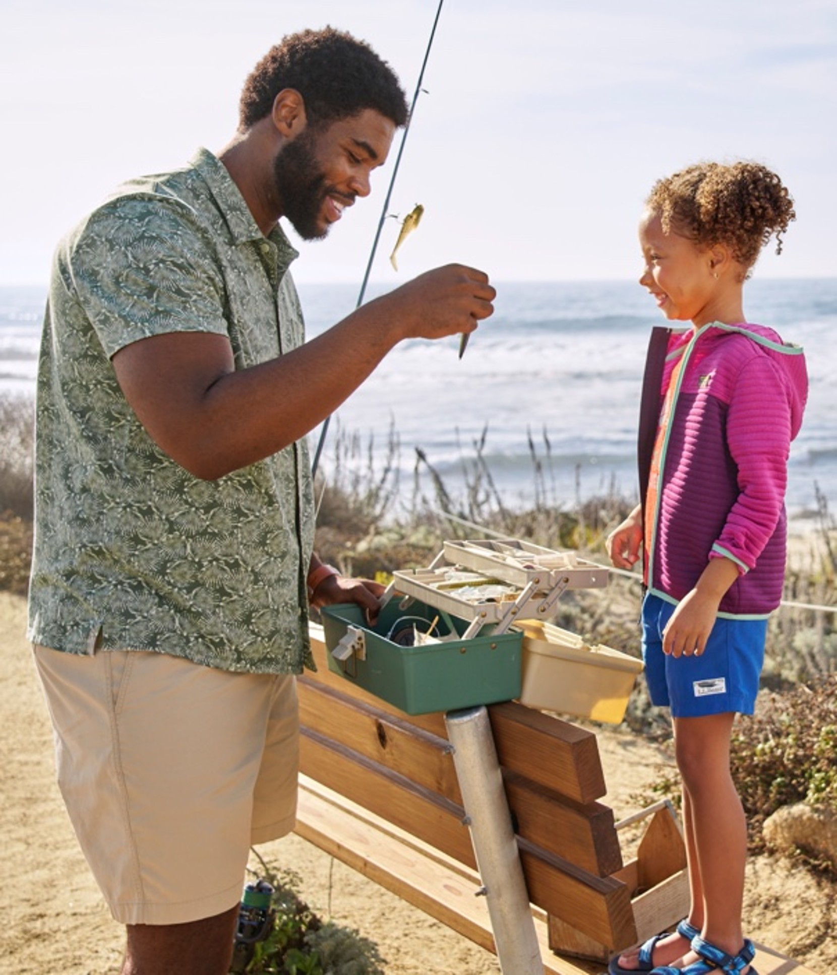 Man and child in summer clothes at the ocean getting ready to go fishing.