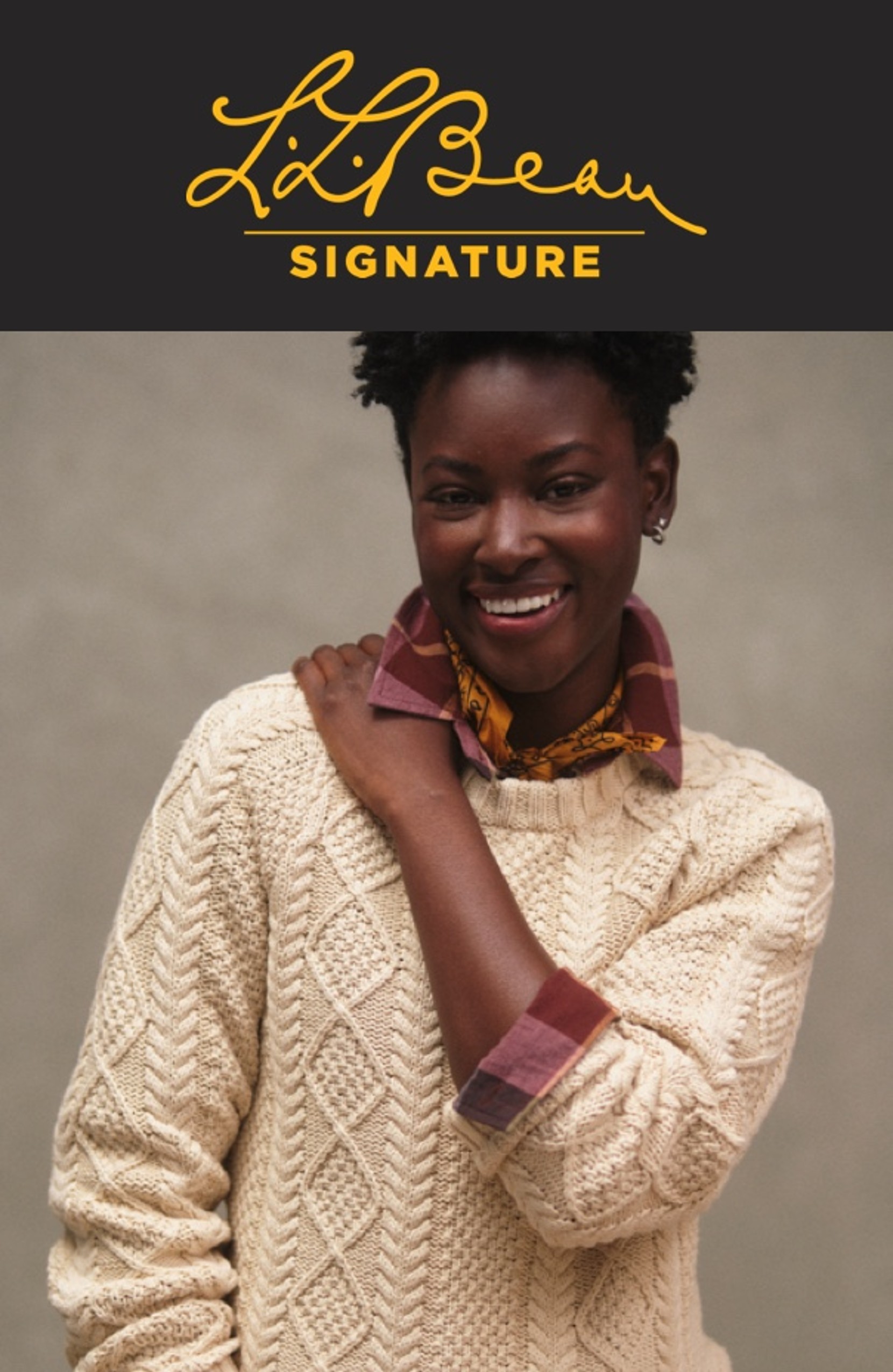 A woman wearing a flannel shirt layered with a cream colored fisherman sweater.
