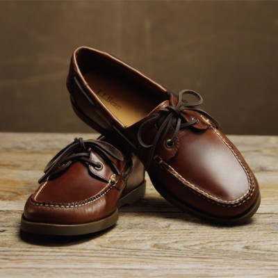 Pair of brown leather boat shoes displayed on a wooden surface.