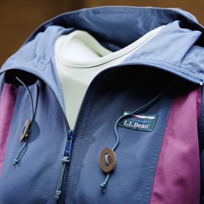 Close up of L L Bean anorak with blue, plum, and green color blocking, front zipper, and adjustable hood drawcords.