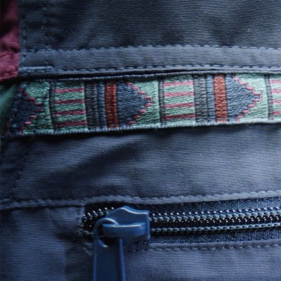 Close-up of woven geometric trim detail and zippered pocket on a blue L L Bean anorak.