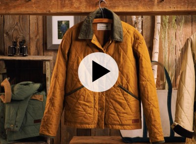 Video thumbnail showing a tan quilted field coat with corduroy collar hanging in a rustic store setting.