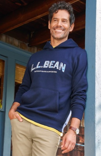 Person wearing a navy L. L. Bean hoodie and tan pants, standing casually near a wooden doorway.