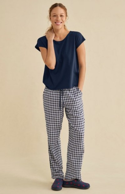 Navy T‑shirt paired with black‑and‑white check lounge pants and dark slip‑on shoes.