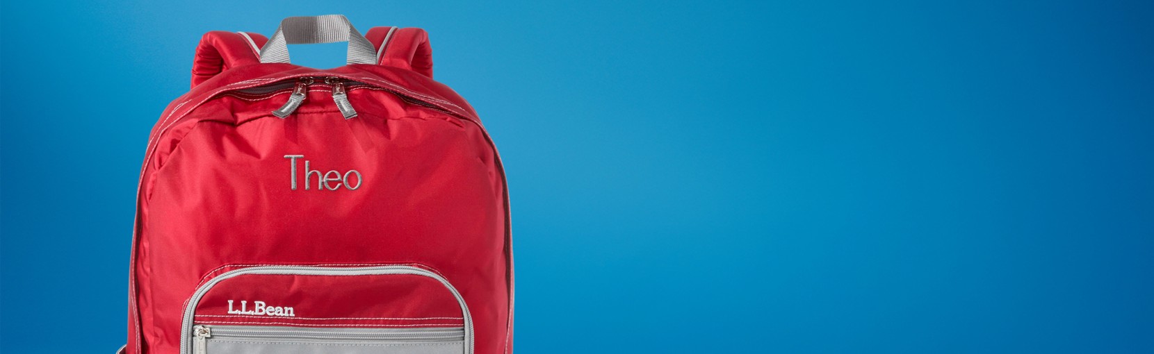 Red L. L. Bean backpack against a blue gradient background, with front zipper pocket and top handle visible.