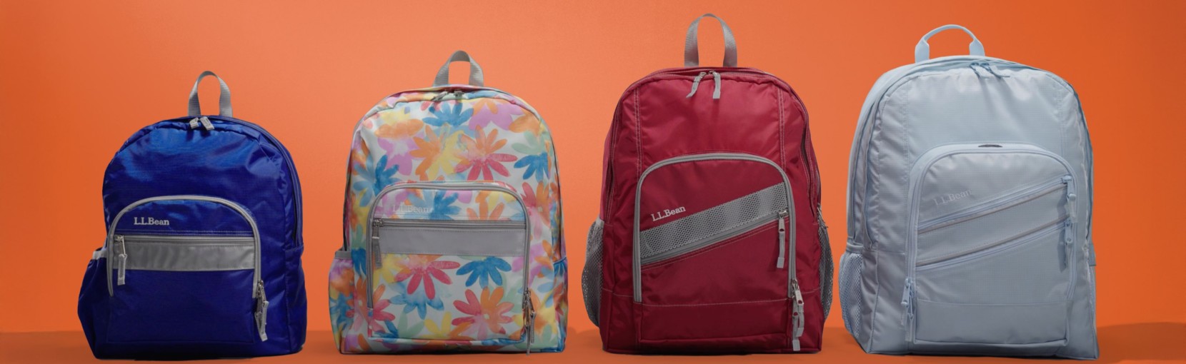 A mix of solid color and patterned backpacks stand side by side against a bright orange background.
