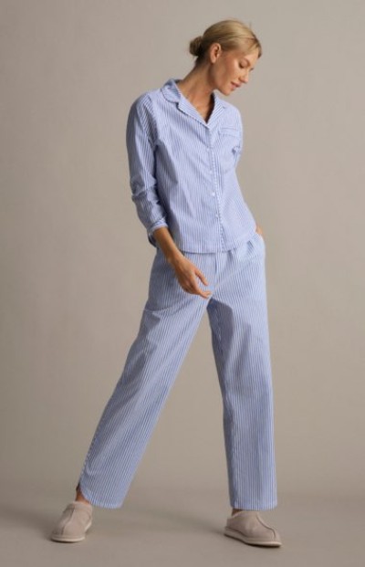 Person walking in a studio wearing a light blue matching top and pants pajama set.