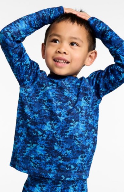 Child in a blue patterned top standing with hands raised above the head.