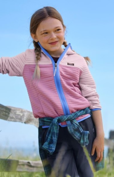 Child in a pink quarter-zip fleece leaning on a wooden fence outdoors.