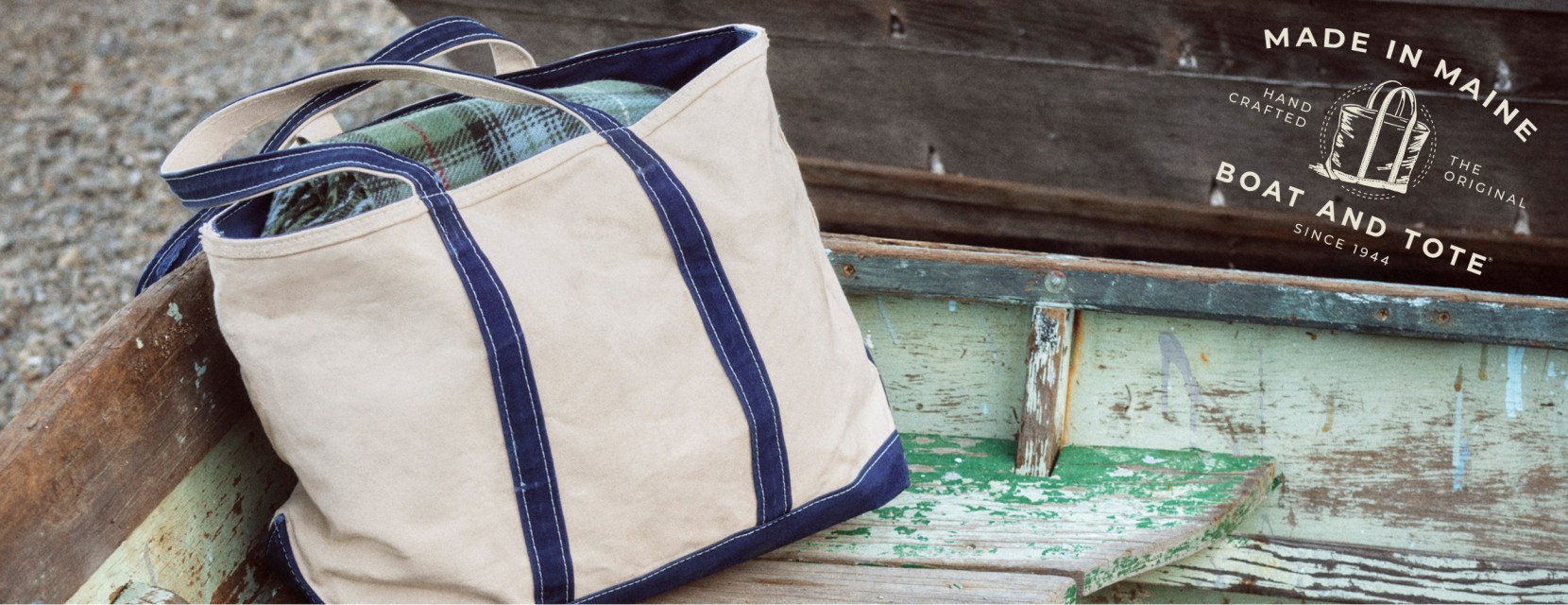 Canvas tote bag resting inside a weathered wooden boat, with text and an icon that says Made in Maine since 1944.
