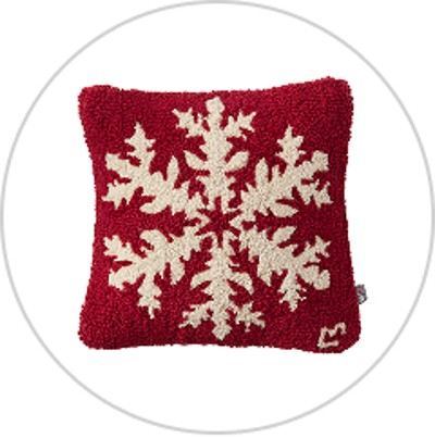 A red wool hook throw pillow with a single snowflake across the front.