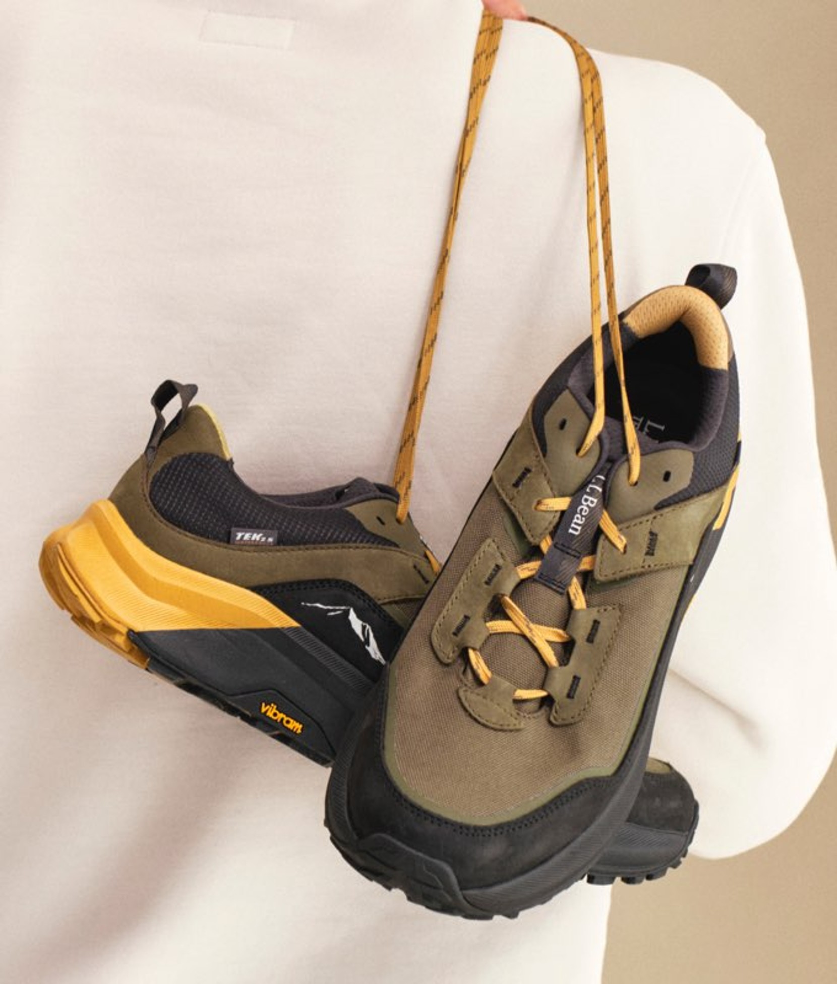 Pair of rugged lace-up boots in brown and green hanging by laces.