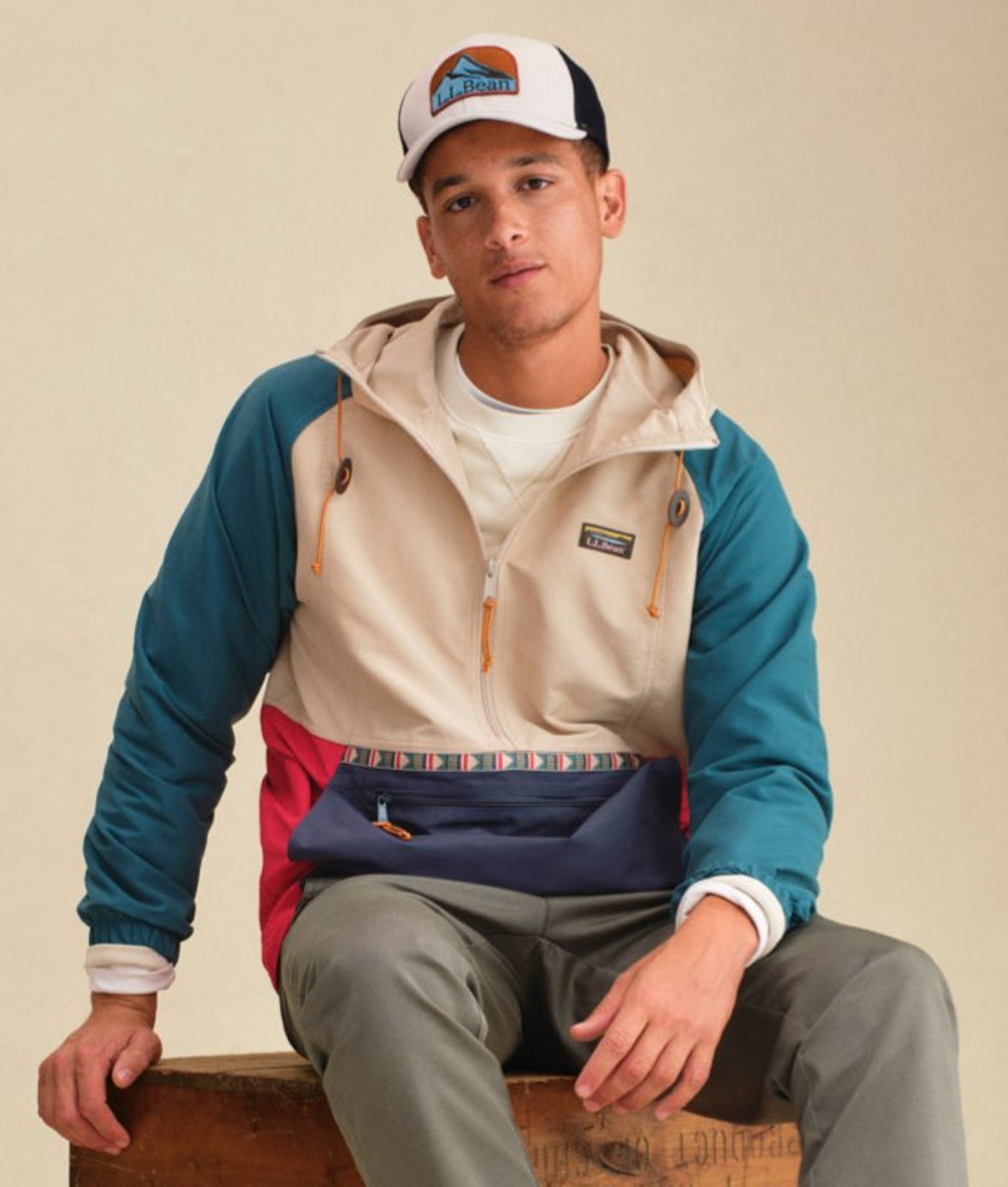 Colorblock men’s outerwear jacket worn by a seated model. 