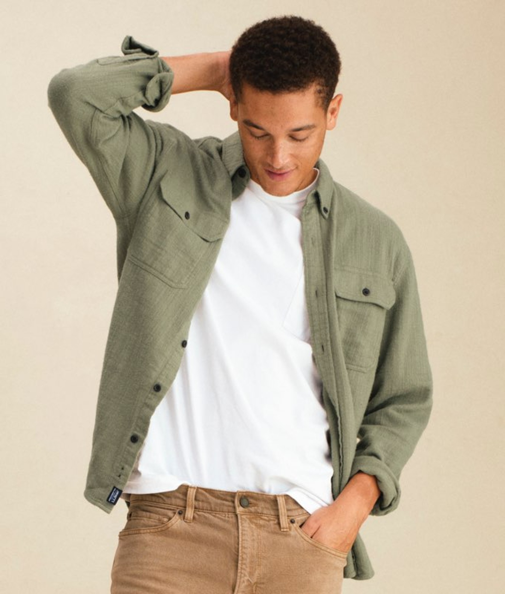 Man standing wearing a green plaid flannel shirt over a white tee.