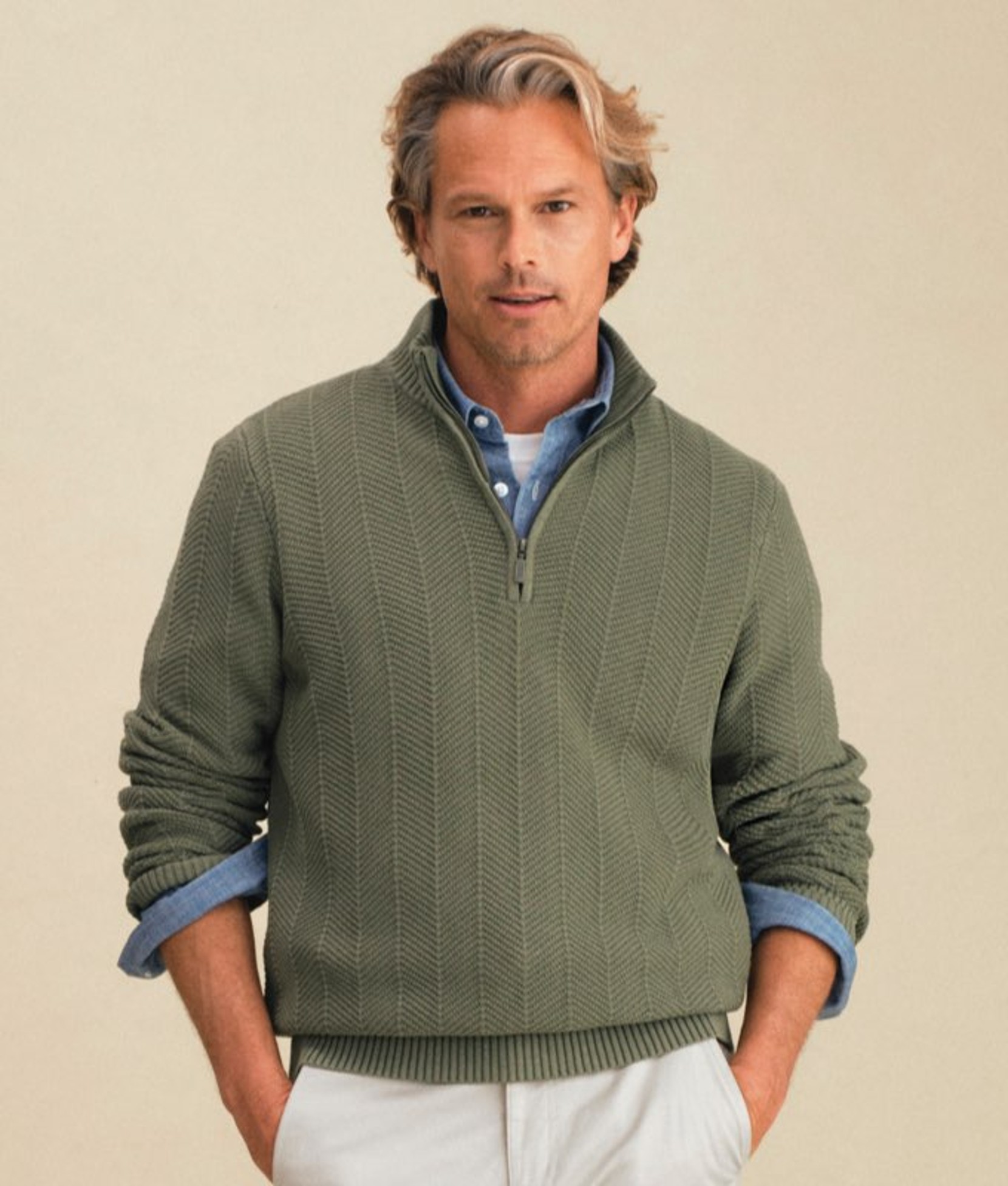 Green men’s pullover worn by a model with hands in pockets. 