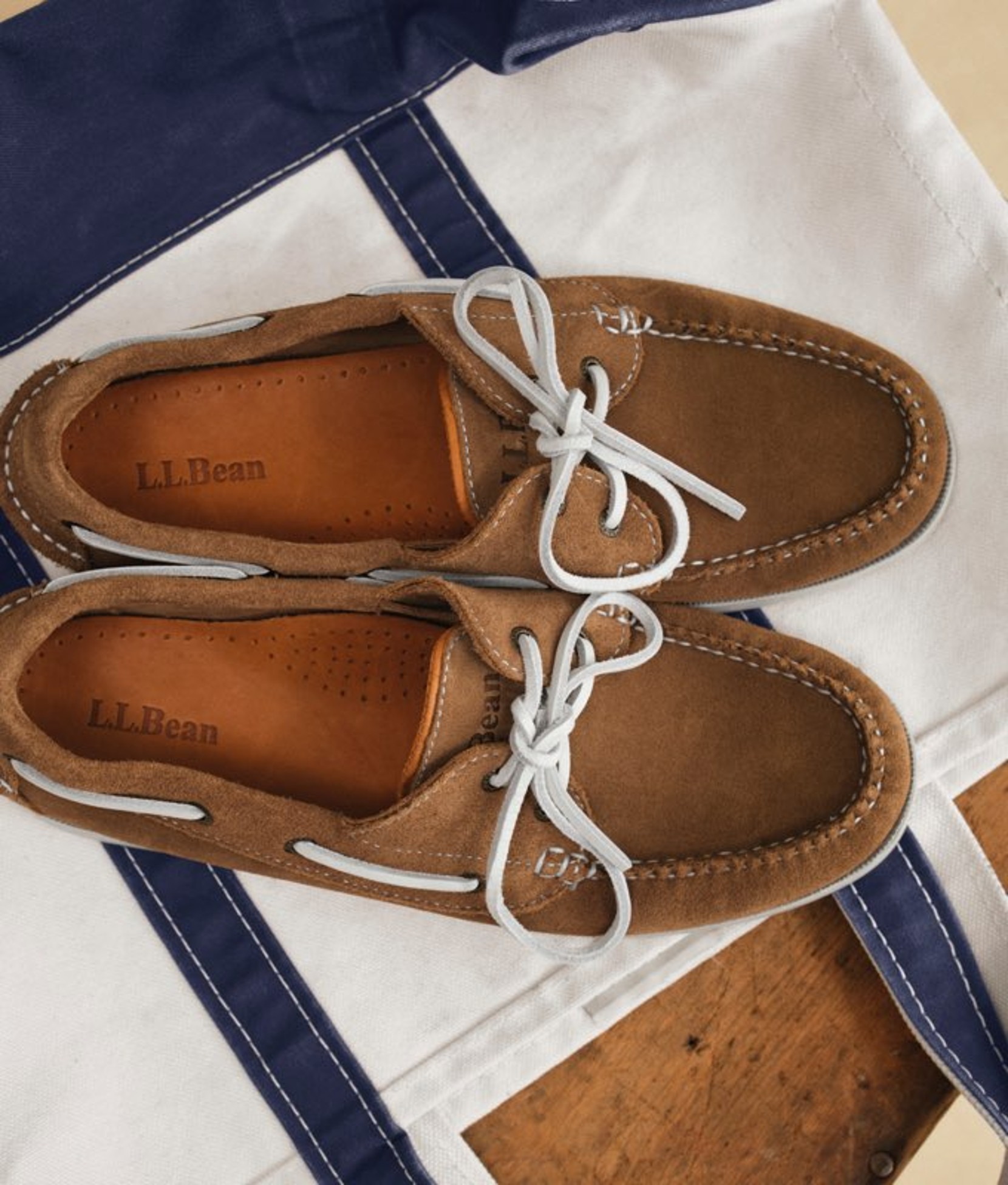 Brown women’s boat shoes displayed on a flattened tote bag. 