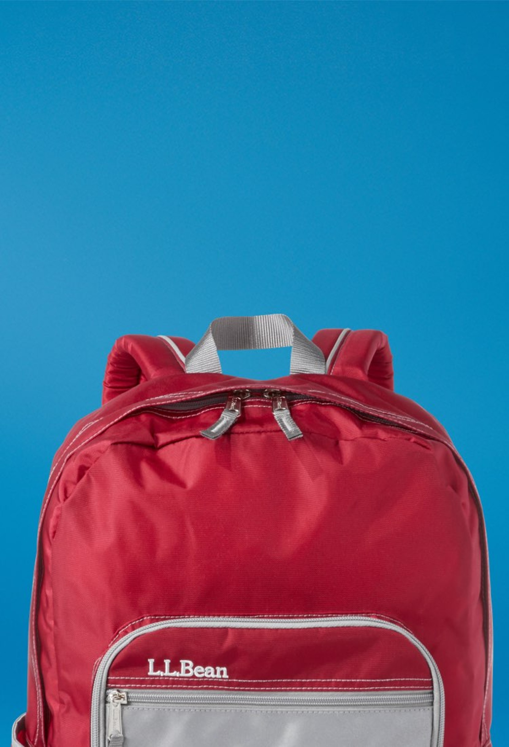 Red L L Bean backpack against a blue gradient background, with front zipper pocket and top handle visible.