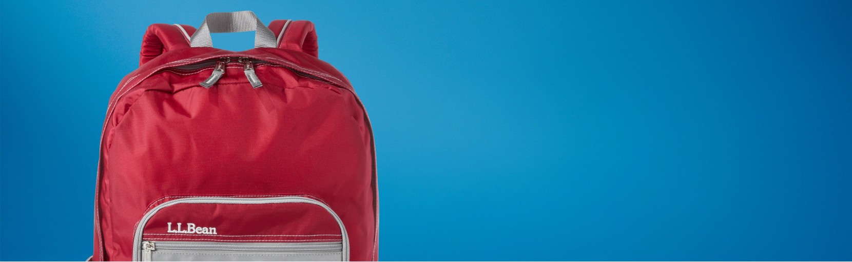 Red L L Bean backpack against a blue gradient background, with front zipper pocket and top handle visible.
