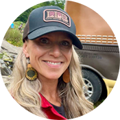 Portrait of Kelly smiling and wearing a baseball hat.