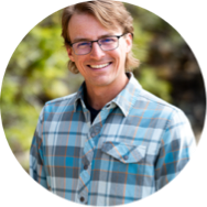 Tucker V smiling in a plaid shirt.