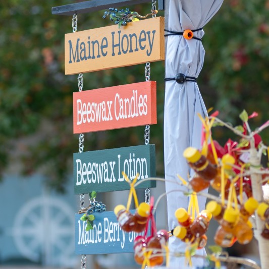 Painted wooden signs on an outdoor craft booth.
