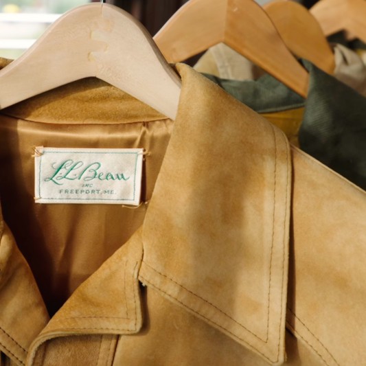 Close up of an L.L.Bean logo tag inside a vintage coat on a hanger.