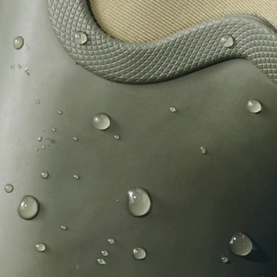 Close up image of water droplets bead on a textured, waterproof surface, highlighting its water‑resistant material.