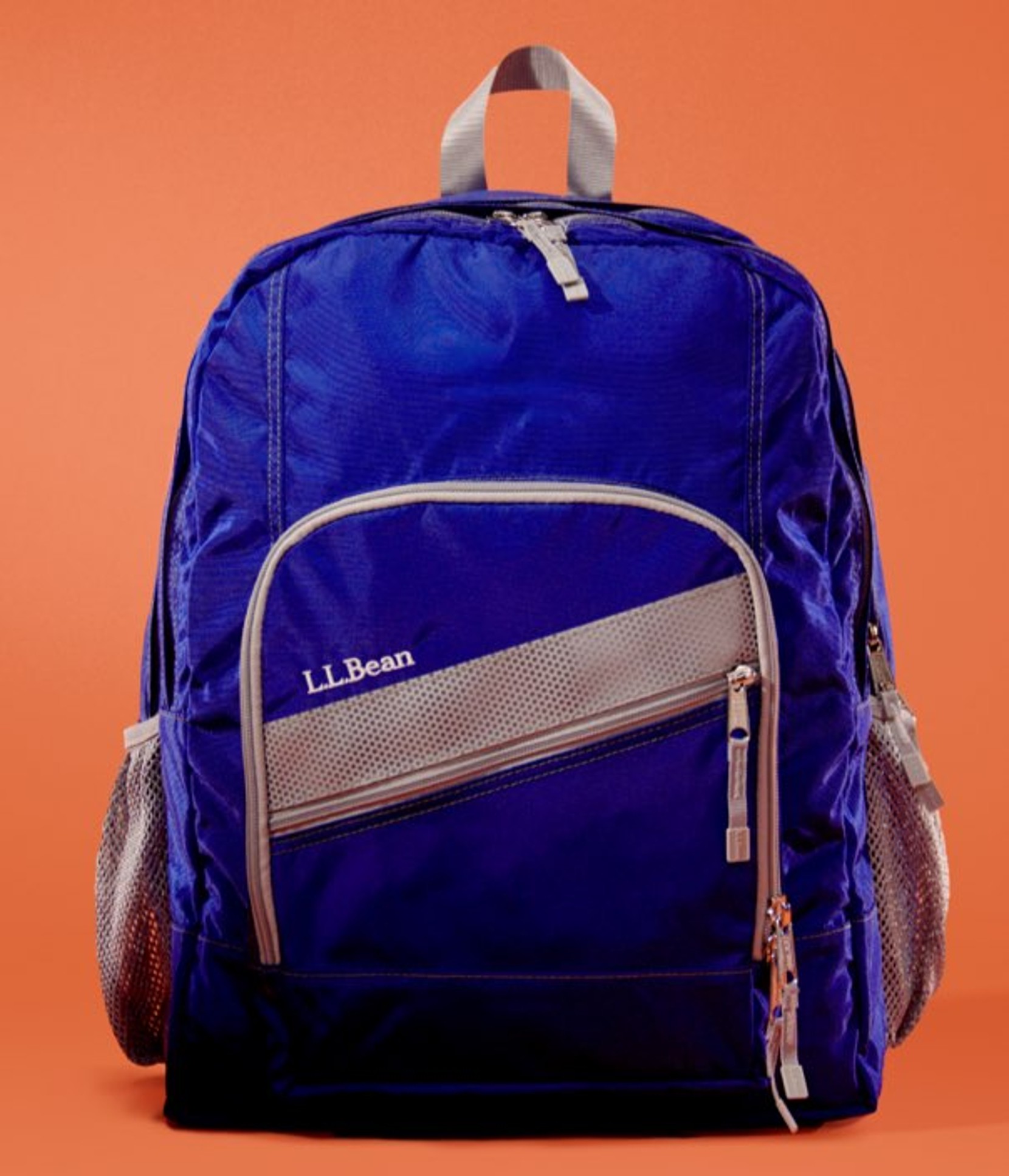 A solid royal blue backpack sits against a bright orange background.