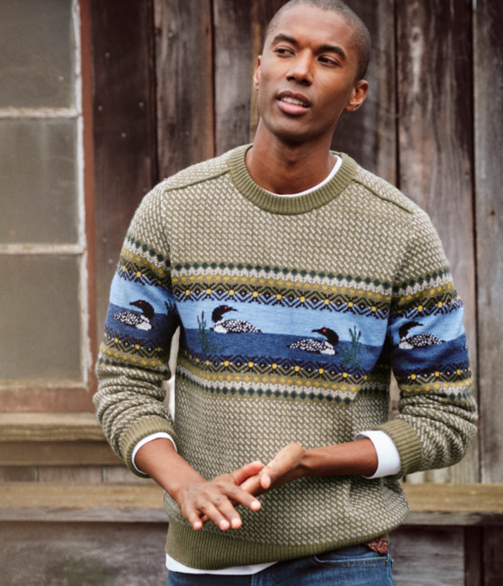 Person in a patterned sweater with birds on the front standing outdoors.