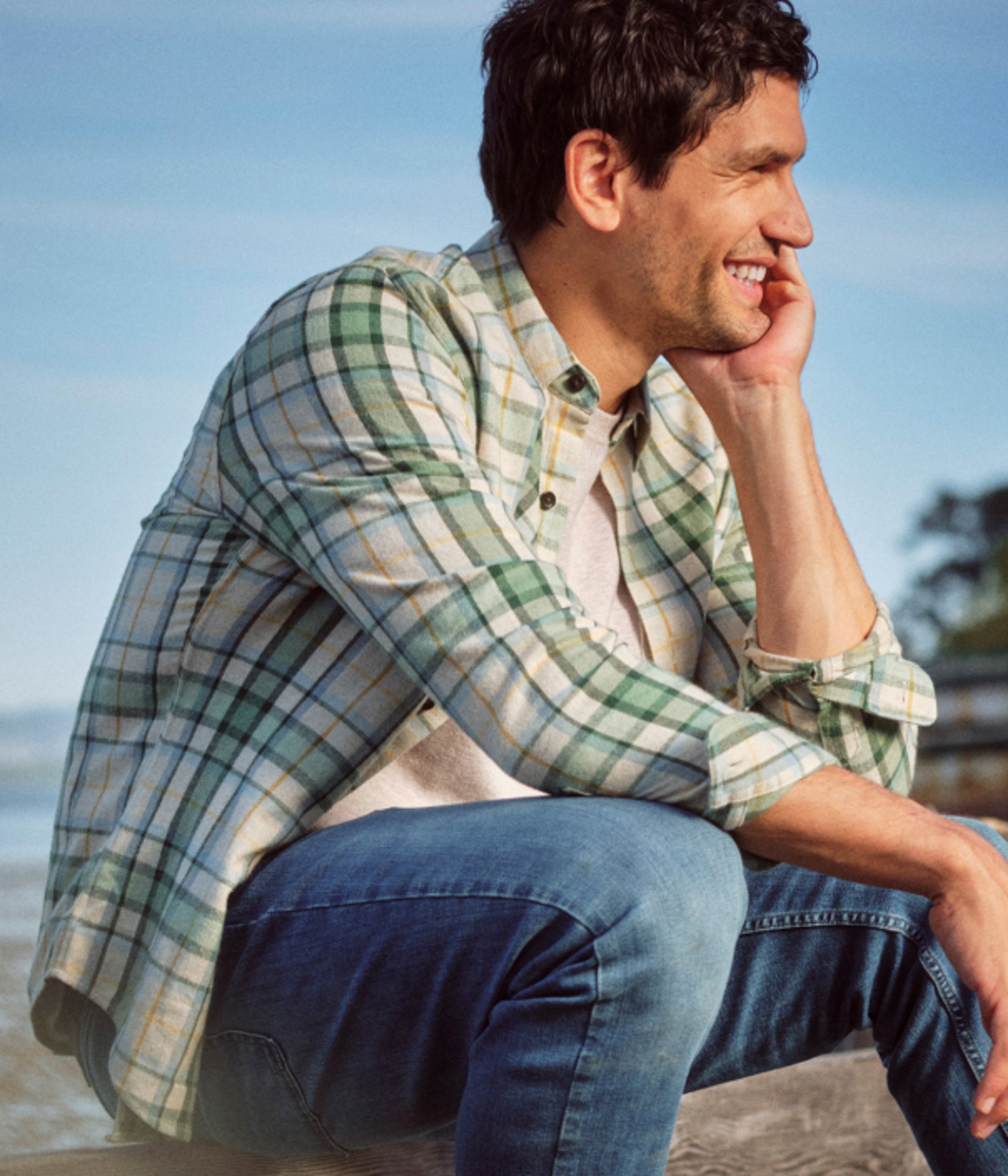 Person seated outdoors wearing a green plaid shirt.