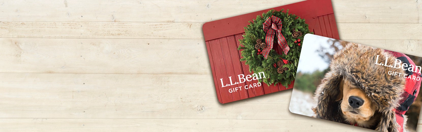 2 L L Bean gift cards on a light wood background.